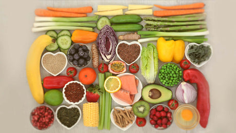 Colourful assortment of foods high in vitamins including fruits, vegetables, seeds, nuts, and fish - Kaizen Naturals