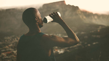 Man drinking a bottle of water looking off into the distance - Kaizen Naturals