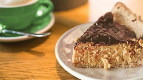Slice of Protein Peanut Butter Pie next to green coffee cup - Kaizen Naturals vegan recipe