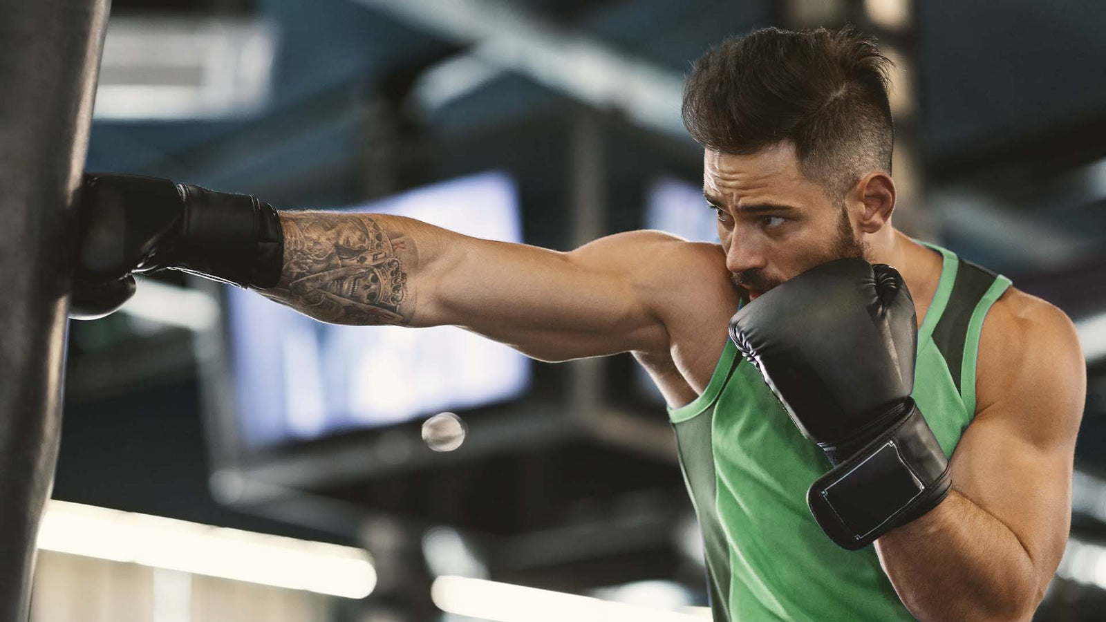 Man wearing boxing gloves, hitting a punching bag.